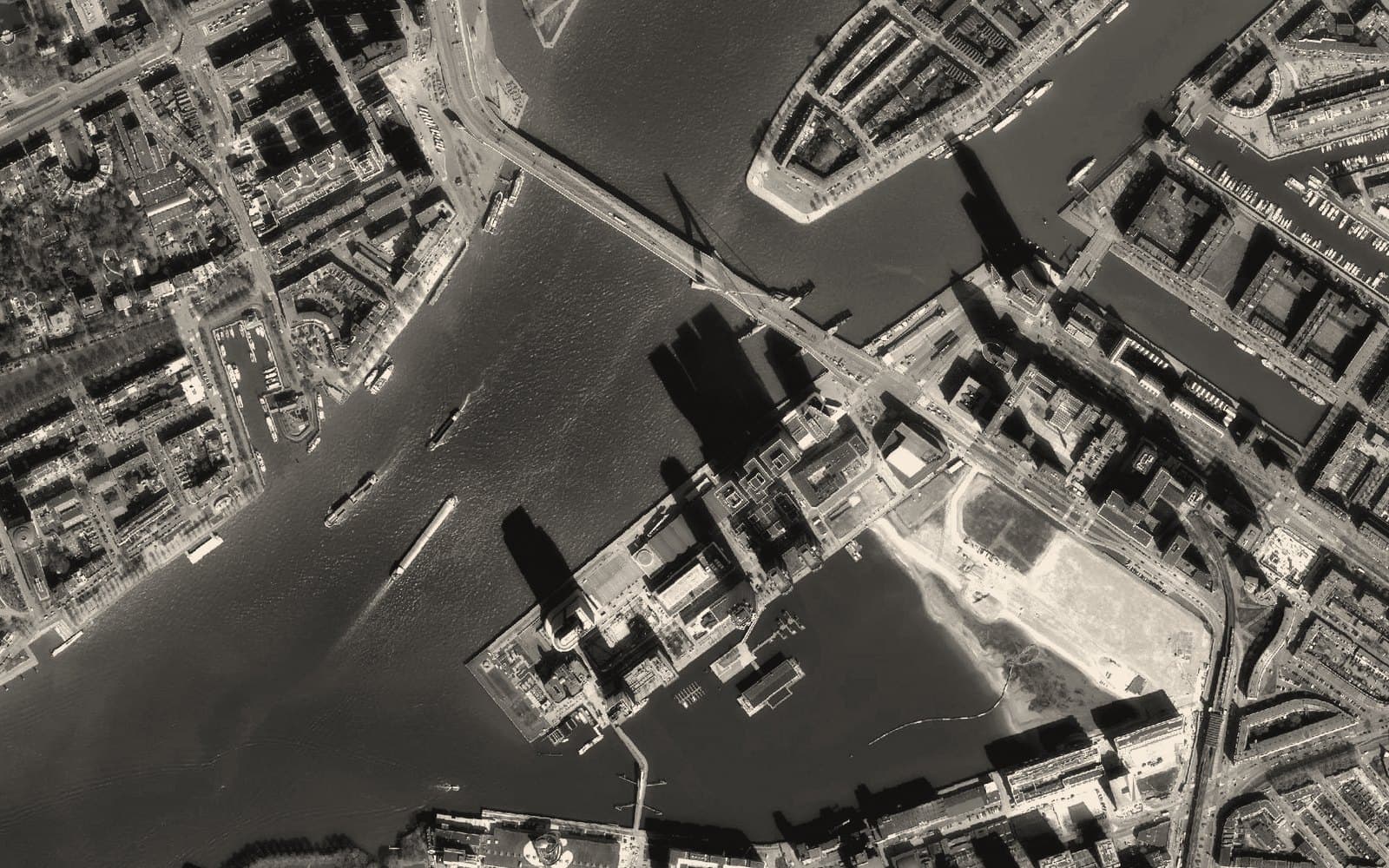 Aerial view of a river through a port city with many vessels underway: many actors, one shared picture