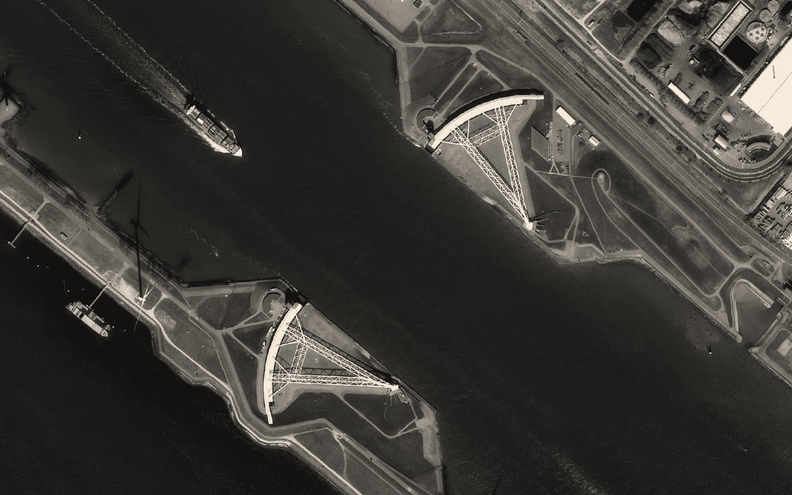 Aerial view of a storm surge barrier flanking a shipping channel: infrastructure built for the shock, not the forecast
