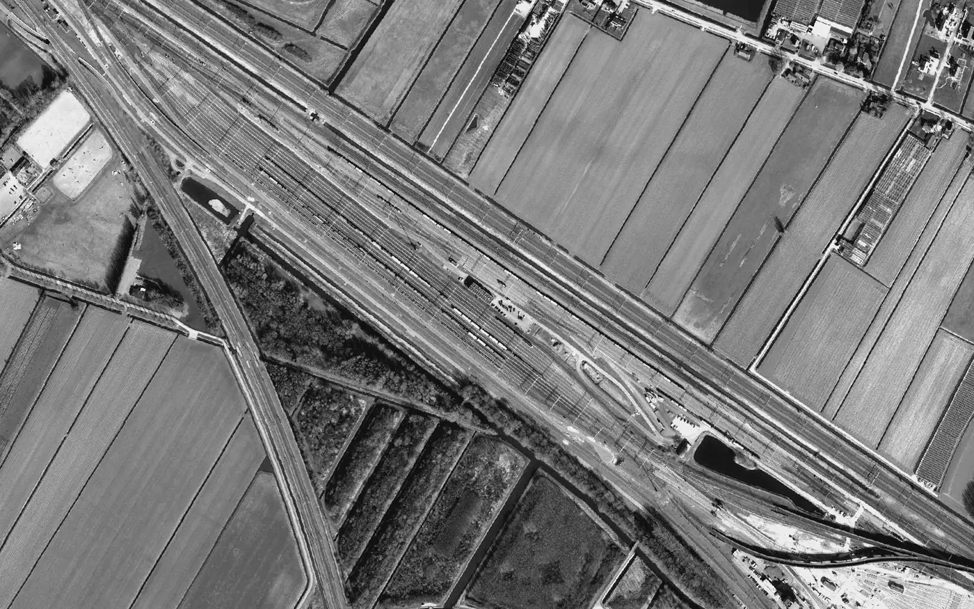 Aerial view of a rail marshalling yard, freight trains fanned across the tracks: coordination made visible