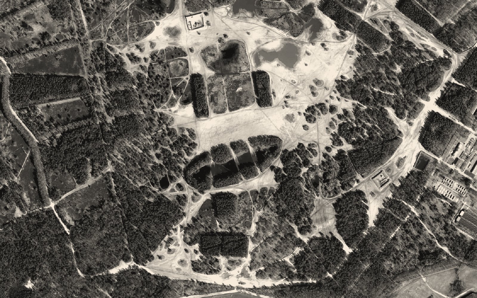 Aerial view of a military training area, sandy terrain webbed with vehicle tracks