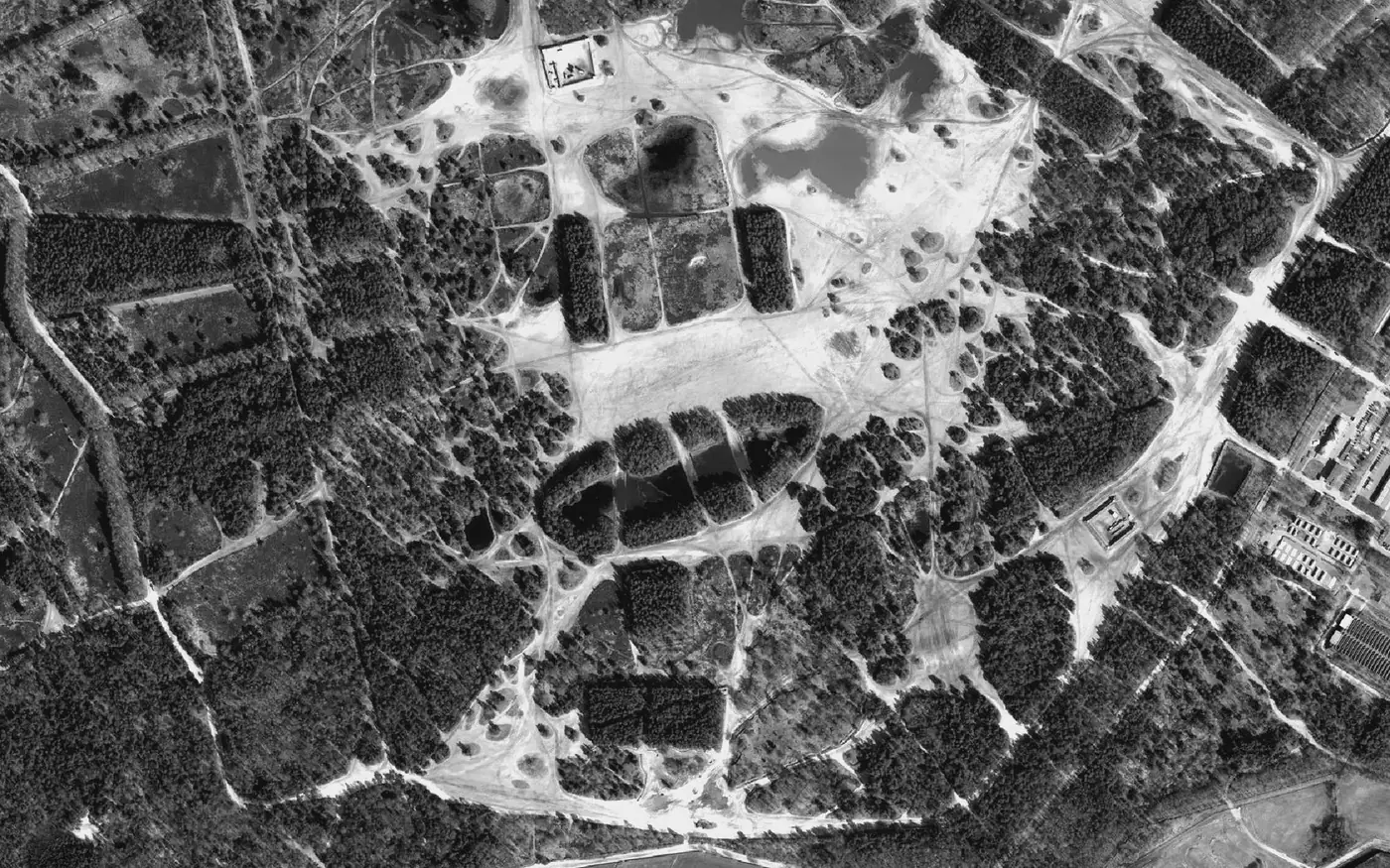 Aerial view of a military training area, sandy terrain webbed with vehicle tracks